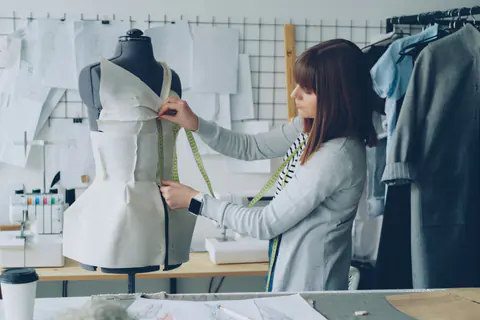 Costumière drapant un vêtement sur un mannequin de couture en atelier